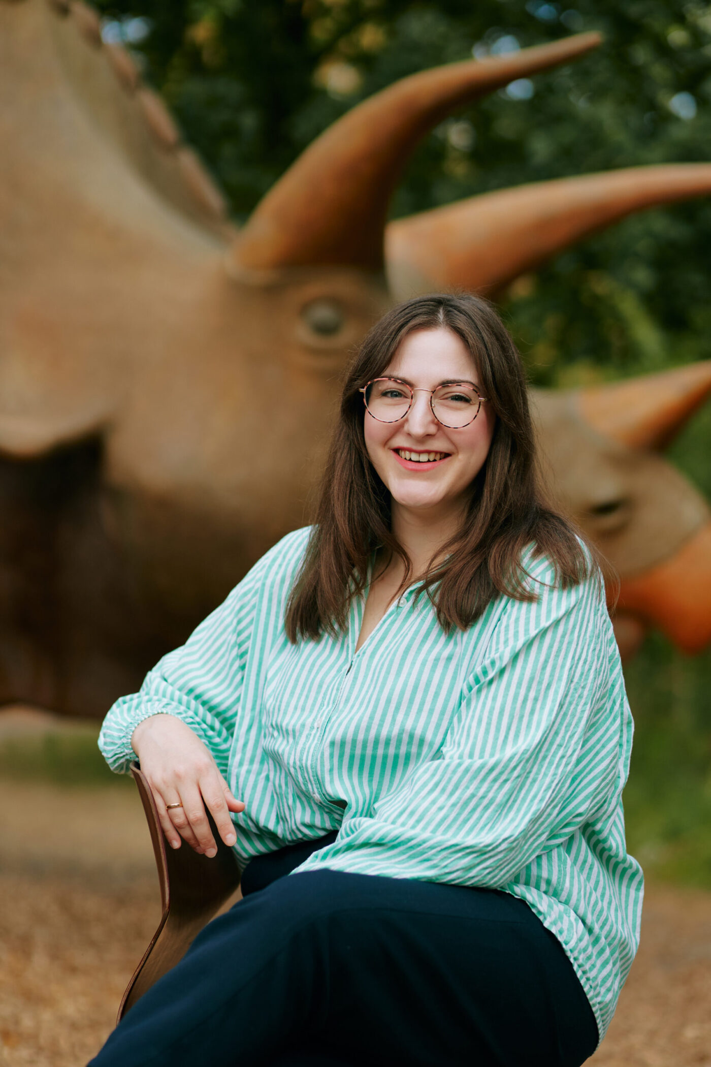 Startseite Barbara Nick-Labatzki Freie Rednerin in Osnabrück, Münster und Umgebung Freie Rednerin Barbara Nick-Labatzki sitzt lächelnd vor einem Dino | Freie Trauungen und Kinderwillkommensfest in Osnabrück, Münsterland und deutschlandweit
